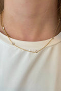 Gold necklace worn by a person on a plain background