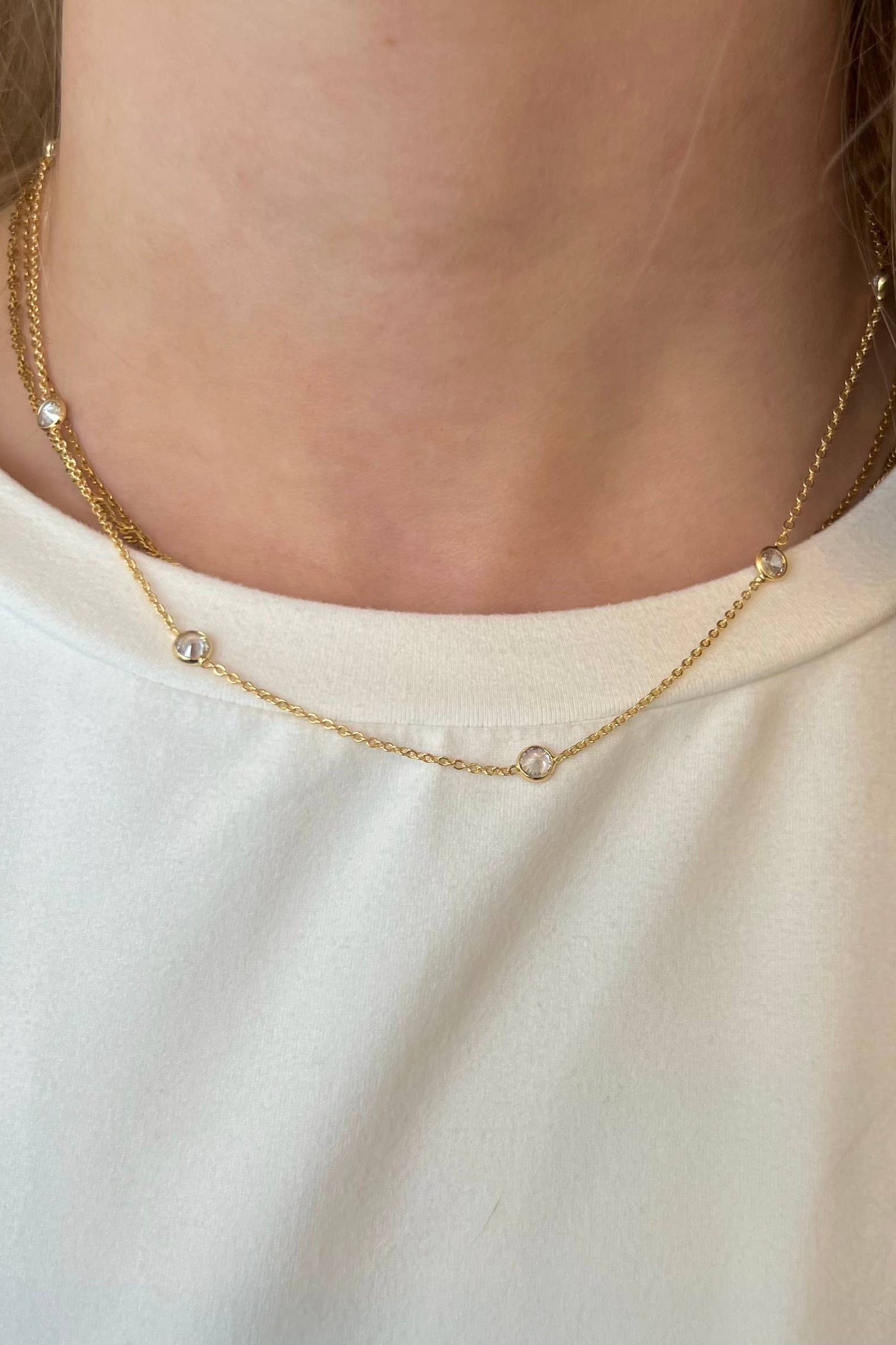 Gold necklace worn by a person on a plain background