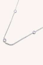 Silver necklace with small diamonds on a light gray background