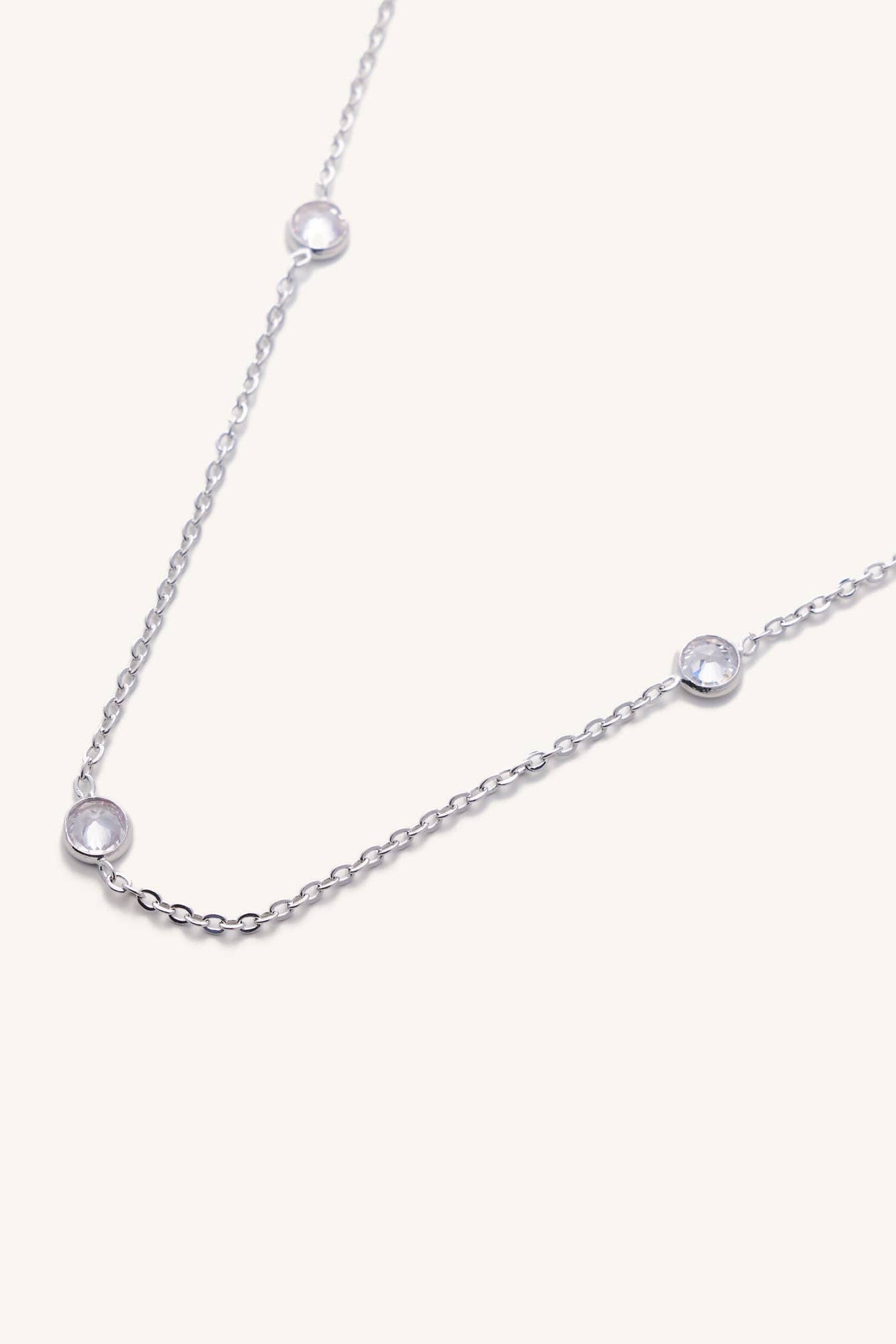 Silver necklace with small diamonds on a light gray background