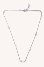 Silver necklace with small diamonds on a light purple background