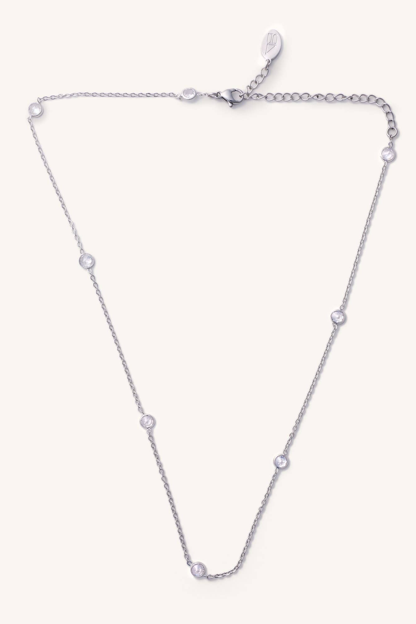 Silver necklace with small diamonds on a light purple background
