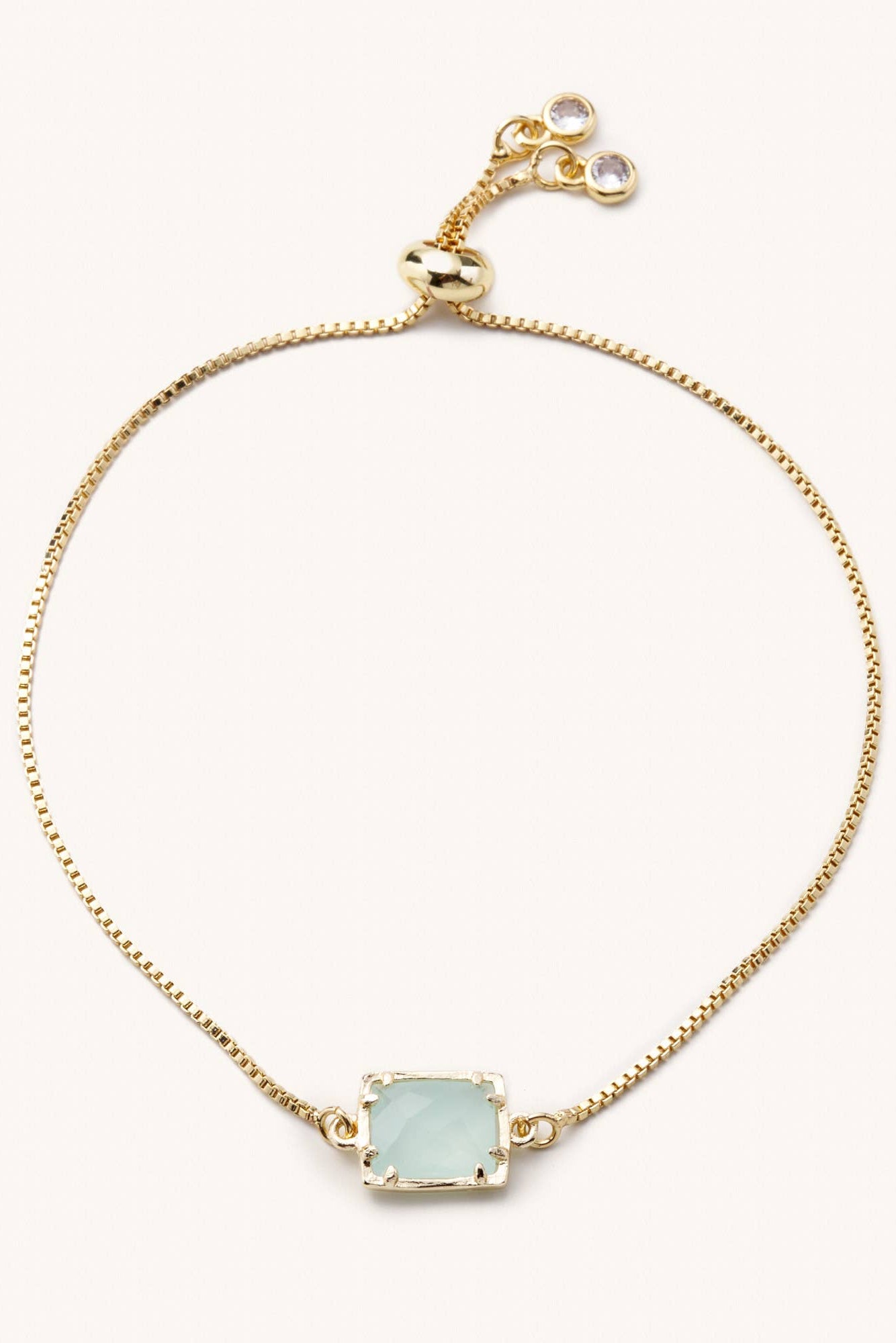 Gold bracelet with a light blue gemstone on a white background