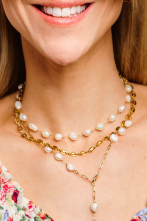 Woman wearing a floral dress and pearl necklace with a beige background