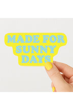 Hand holding a yellow sign with 'MADE FOR SUNNY DAYS' text on a white background