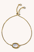 Gold bracelet with a central gemstone on a white background