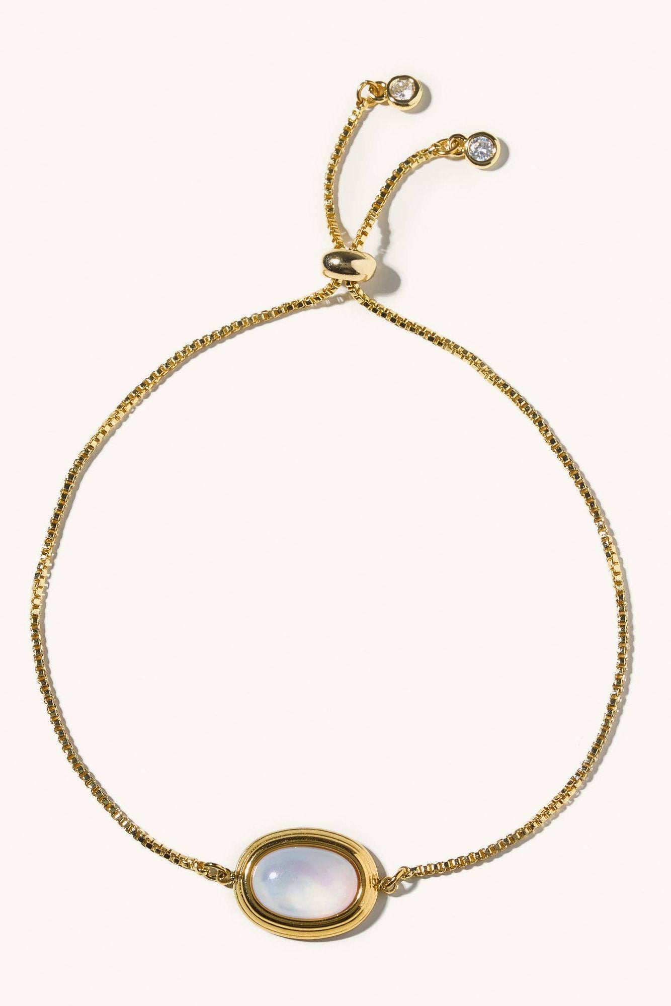 Gold bracelet with a central gemstone on a white background