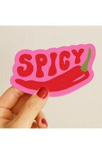 Hand holding a 'SPICY' sticker with a red chili pepper on a beige background