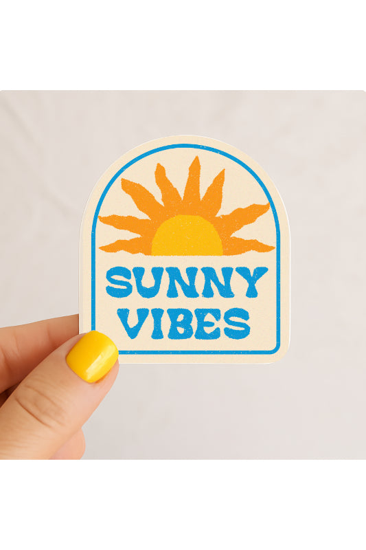 Sticker with sun design and 'Sunny Vibes' text held by a hand with yellow nail polish on a light gray background.
