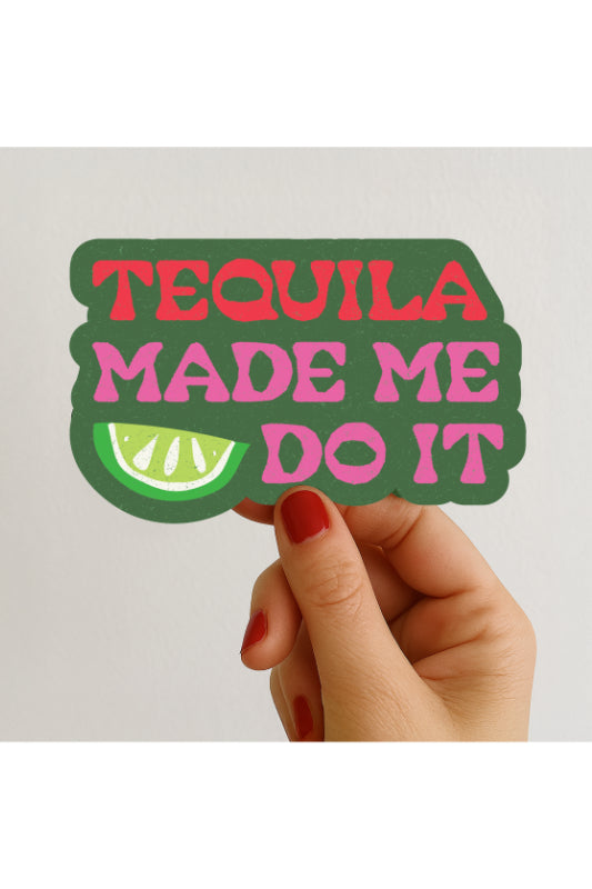 Hand holding a sticker with 'Tequila Made Me Do It' text and lime graphic on a plain background