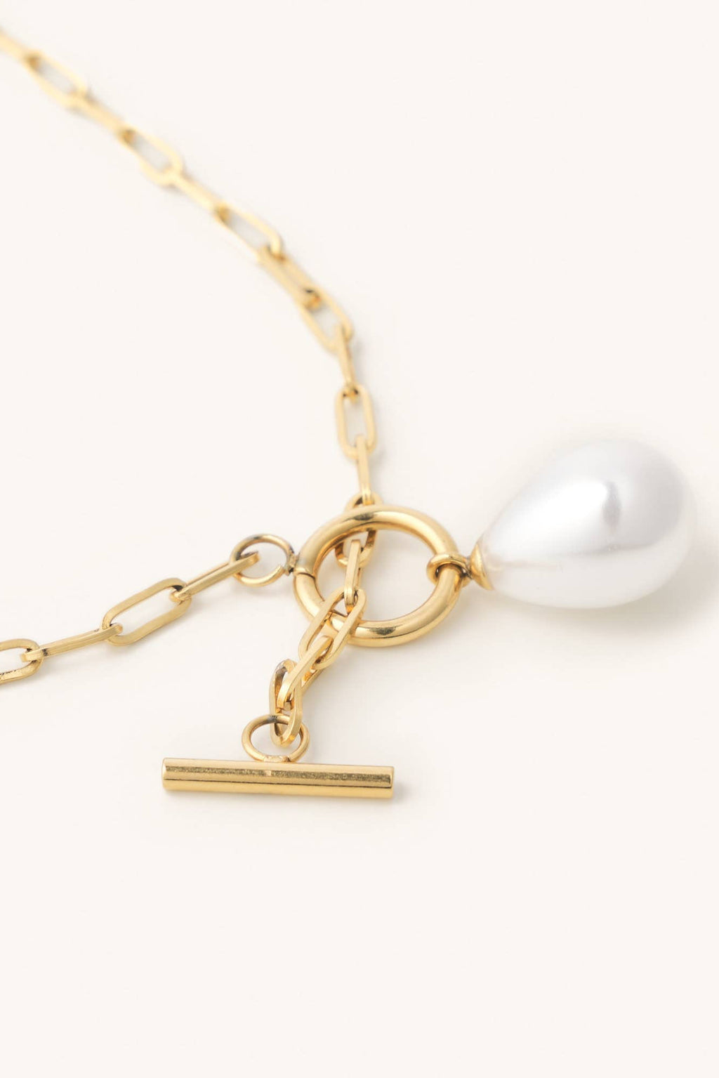 Gold necklace with a pearl pendant on a white background